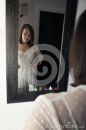 Asian woman puts on her white satin nightwear Stock Photo