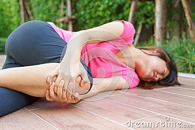 Asian woman runner laying on the floor and touching her injured Stock Photo