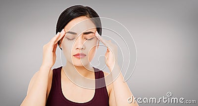 Asian woman`s migraine severely, suffering korean,chinese girl isolated on grey background, healh care concept Stock Photo