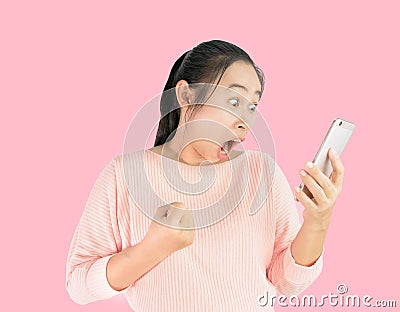 Asian woman shocked what she see in the smartphone and made a gesture of success, Isolated on pink background Stock Photo