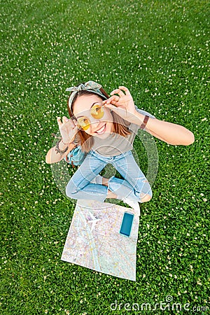 Asian woman sitting on grass in park with open map and smartphone and airplane toy. Tourism and travel concept Stock Photo