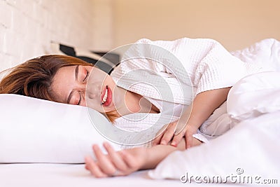 Asian woman sleeping on the bed and grinding teeth,Female tiredness and stress Stock Photo