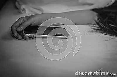 Asian woman sleeping in bed at home and hand holding mobile phone. Woman using smartphone in bedroom. Young woman addicted using Stock Photo