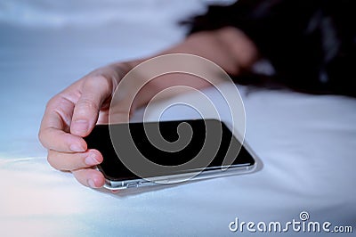 Asian woman sleeping in bed at home and hand holding mobile phone. Woman using smartphone in bedroom. Young woman addicted using Stock Photo