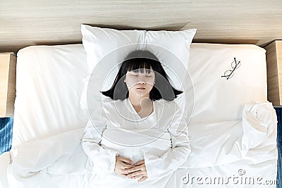 Asian woman sleeps on white bed after exhausted and tried all day Stock Photo