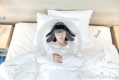 Asian woman sleeps on white bed after exhausted and tried all day Stock Photo