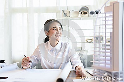 Asian woman smart architect look out the window to rest one's eyes or relax while working in light and bright office room, Stock Photo