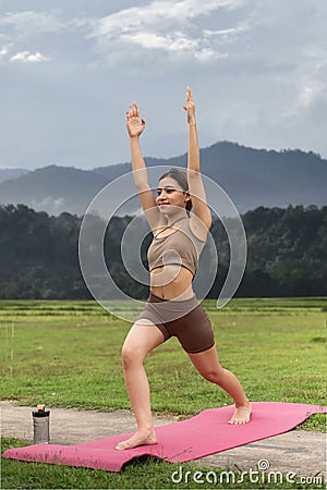 Asian woman sporty practicing yoga at public park outdoor stretching her body. Healthy active lifestyle Stock Photo