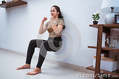 asian woman squating against the wall at home Stock Photo