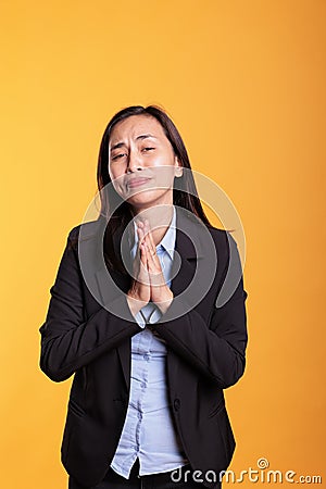 Asian woman standing with hands in praying gesture Stock Photo