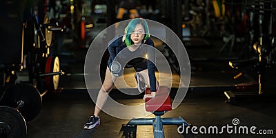 Asian woman with strong and muscular body training on bent over row dumbbell with bench staring at the camera to build back and Stock Photo