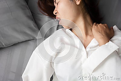 Asian woman suffering from neck sprain or a crick in her neck during sleeping in the bed Stock Photo