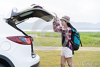 Asian woman travel camping on vacation. A girl open and close back door hatchback car white color on nature green view Stock Photo