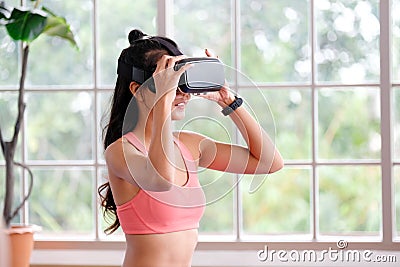 Asian woman virtual reality headset while exercise at home, Healthy asia girl wearing vr glasses for interactive exercise, e sport Stock Photo