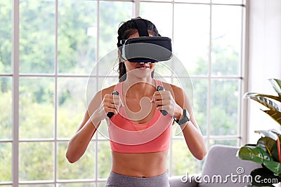 Asian woman virtual reality headset while exercise at home, Healthy asia girl wearing vr glasses for interactive exercise, e sport Stock Photo