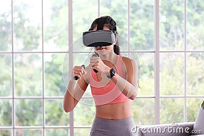 Asian woman virtual reality headset while exercise at home, Healthy asia girl wearing vr glasses for interactive exercise, e sport Stock Photo