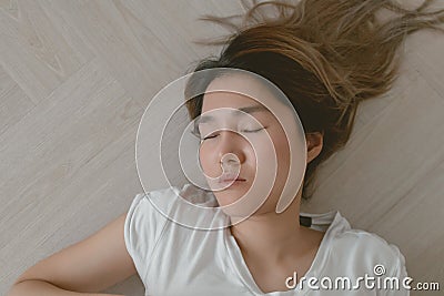 Asian woman wears white t-shirt lie on the wooden floor exhaustedly. Stock Photo