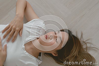 Asian woman wears white t-shirt lie on the wooden floor exhaustedly. Stock Photo