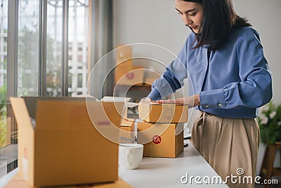 Asian woman worker or seller packing cardboard ecommerce shipping order box for dispatching Stock Photo