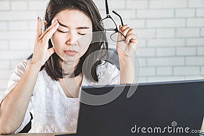Asian woman worker suffering from eye strain hand holding eyeglasses Stock Photo
