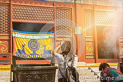 Asian woman worshipping with incense sticks at a colorful Buddhist temple Editorial Stock Photo