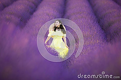 Asian woman in yelllow dress is enjoy walking into Lavender plantation field during summer time Stock Photo