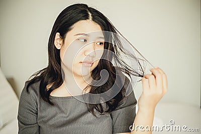 Asian women bore and moody with damaged hair and split ends due to lack of nourishment Stock Photo