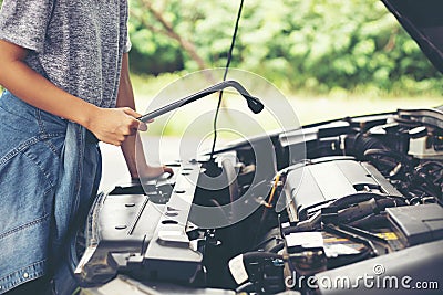 Asian women engineer holding a wrench in hand, prepared for the repairs cars on road Stock Photo