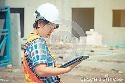 Asian women engineering holds a tablet for use in the inspection of construction sites for accuracy and in accordance with the pla Stock Photo