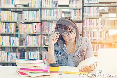 Asian women in library reading and thinking something in a book in a library. Stock Photo