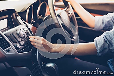 Asian Women press button on car radio for listening to music. Stock Photo