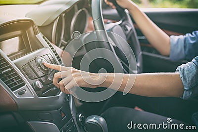 Asian Women press button on car radio for listening to music. Stock Photo