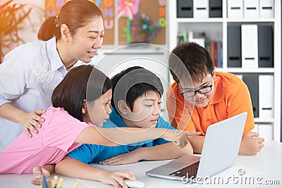 Teacher and Cute Asian children using laptop computer together. Stock Photo