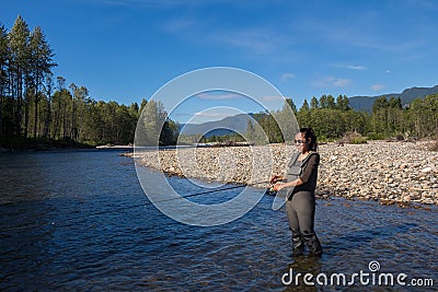 An asian women in waders, enjoying fishing a river in British Columbia, Canada Stock Photo