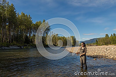 An asian women in waders, fishing a river in British Columbia, Canada Stock Photo