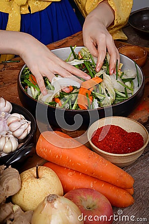 Asian women wearing hanbok, a Korean national costume, cook traditional kimchi, fermented cooking. Stock Photo