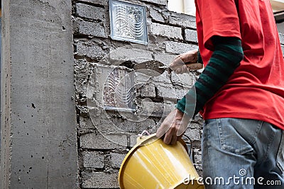 Asian worker installing glass block onto brick wall with mortar Stock Photo