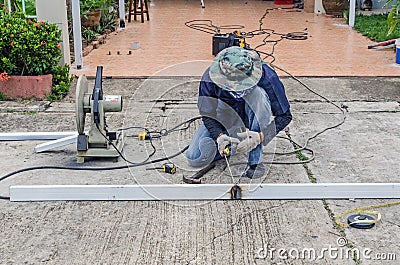 asian worker with machine cutting metal and welded steel to create a roof, local labor construction concept Stock Photo