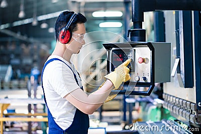 Asian worker operating CNC metal skip in factory Stock Photo