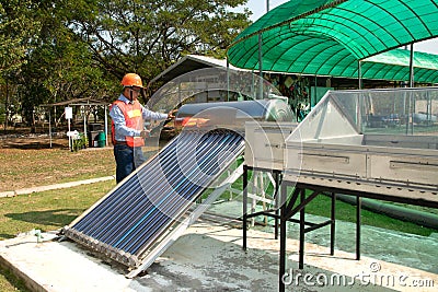 The Asian worker in uniform and helmet checks concentrating Solar Power with Flat Plat collector and Evacuum Tube Collector. Stock Photo