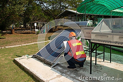 The Asian worker in uniform and helmet checks concentrating Solar Power with Flat Plat collector and Evacuum Tube Collector. Stock Photo