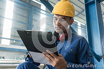 Asian worker writing observations about manufacturing Stock Photo