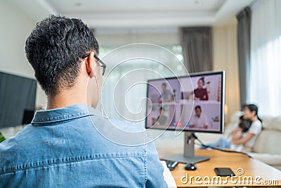 Asian Working business man father talk to colleagues team on virtual video call conference online. Male freelance worker using lap Stock Photo