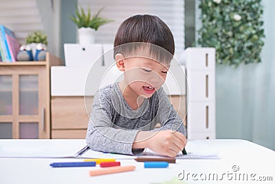 Asian 3 - 4 years old toddler boy child coloring with crayons at home, improve focus in child concept Stock Photo