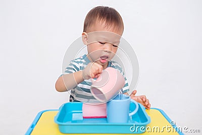 Asian 2 years old toddler boy child having fun pouring water into cup, Wet Pouring Montessori Stock Photo