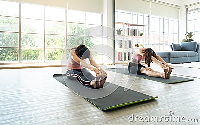 Asian young active two girls stretching legs muscle after workout activity on yoga mat in studio room Stock Photo