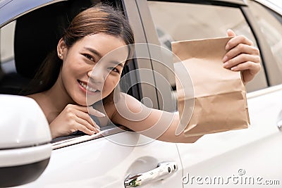 Asian woman holding food bag from drive thru service restaurant Stock Photo