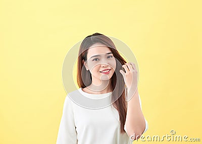 Asian young beautiful woman smiling and touching smooth her hair on yellow background Stock Photo