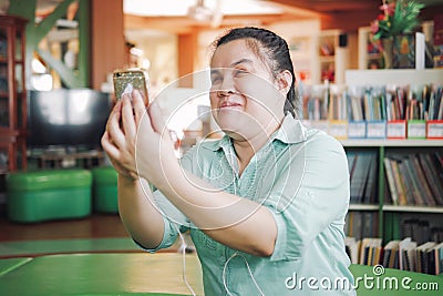 Asian young blind woman disabled person taking selfie or video call using smart phone in creative workplace Stock Photo