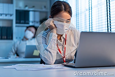 Asian young business woman wear mask, feel tired from work in office. Man and woman employee worker use computer on table overwork Stock Photo